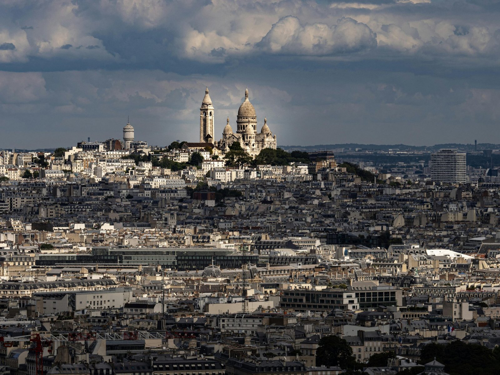 A striking view of the Sacré-Cœur Basilica amidst the Paris skyline with dramatic clouds above.
