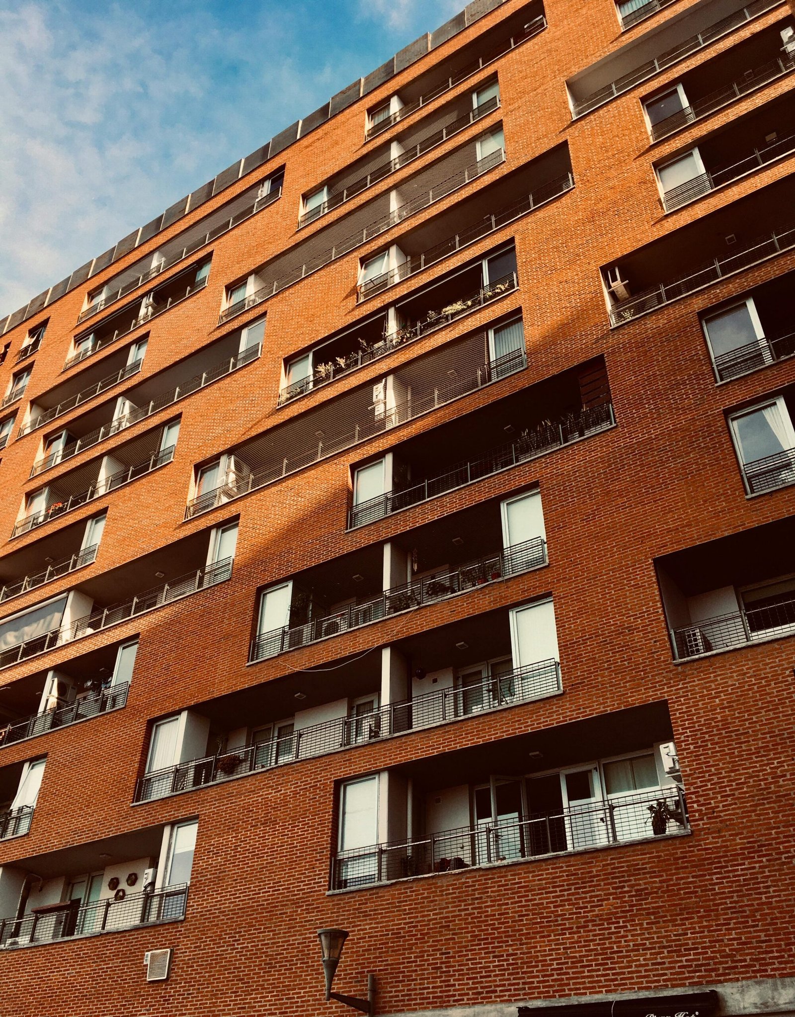 Modern red brick apartment building facade with balconies in Argentina.